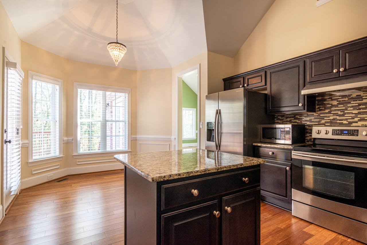 Bright, contemporary kitchen interior featuring marble countertops, hardwood floors, and ample natural light.