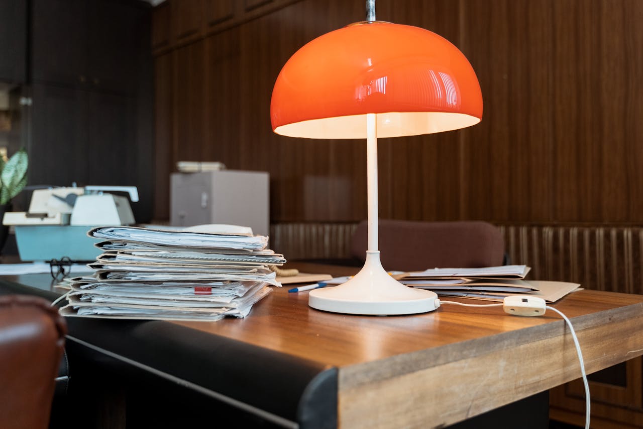 creative A classic office setup featuring a retro orange lamp, documents, and a wooden desk.